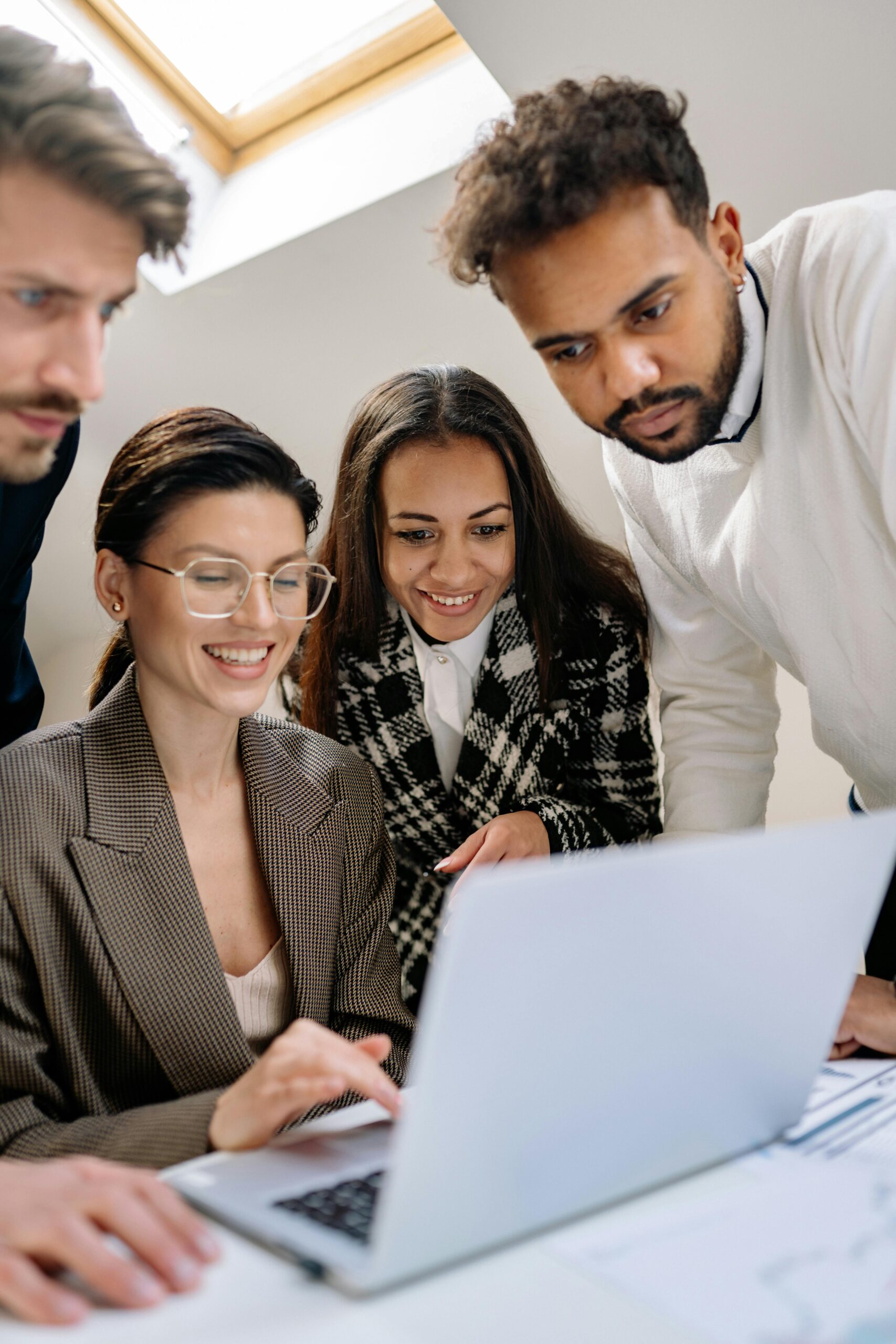 A diverse team of professionals happily collaborating on a laptop at the office.